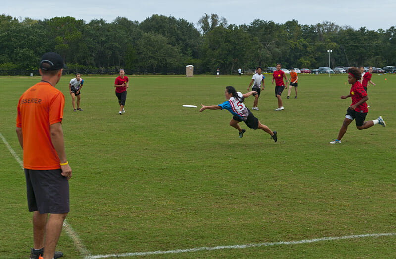A USA Ultimate observer looks on as a player dives to catch the disc.