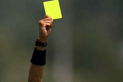 Yellow card being held up by a referee.