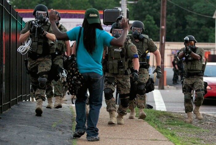 Police from Ferguson, Missouri, point guns at a pedestrian.
